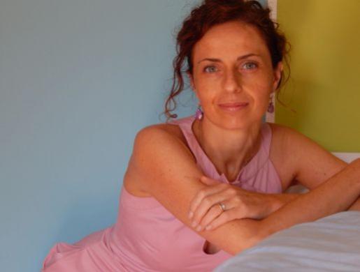 Donna con abito rosa, seduta, sfondo colorato, sguardo sereno e rilassato.